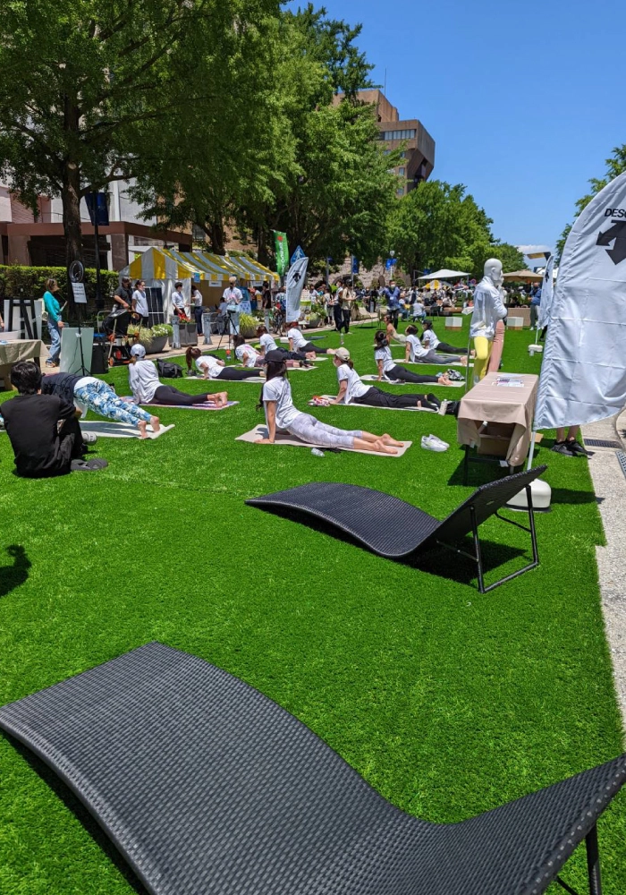 tvk かながわMIRAIストリートの人工芝の上でヨガをする様子